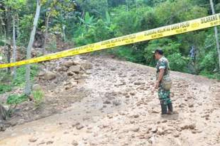 Seorang anggota TNI tengah berjaga di lokasi longsor yang menutup   jalan desa Sepakung, Rabu (19/10/2016) siang.