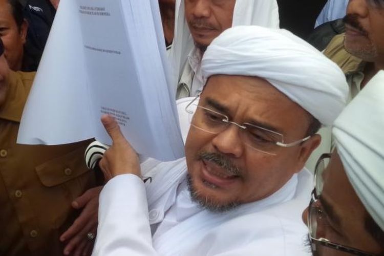 Pemimpin Front Pembela Islam Rizieq Shihab menunjukkan tesisnya sebelum diperiksa oleh penyidik Polda Jawa Barat, Senin (13//2/2017). 