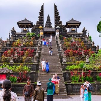 Ilustrasi turis mengunjungi Pura Besakih, Bali. Pura Besakih bukan sekadar tempat ibadah bagi umat Hindu. Terletak di lereng sebelah barat daya Gunung Agung, gunung tertinggi di Pulau Dewata, kompleks ini berdiri megah di Desa Besakih, Kecamatan Rendang, Kabupaten Karangasem, Bali