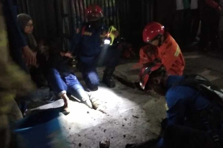 Petugas Sudin PKP Jakarta Timur bantu evakuasi kaki warga Duren Sawit yang jeblos dan tersangkut ke lubang penutup saluran di Komplek Pertokoan Agung, Jalan Buaran Raya, Duren Sawit, Jakarta Timur, Selasa (21/1/2020) malam.
