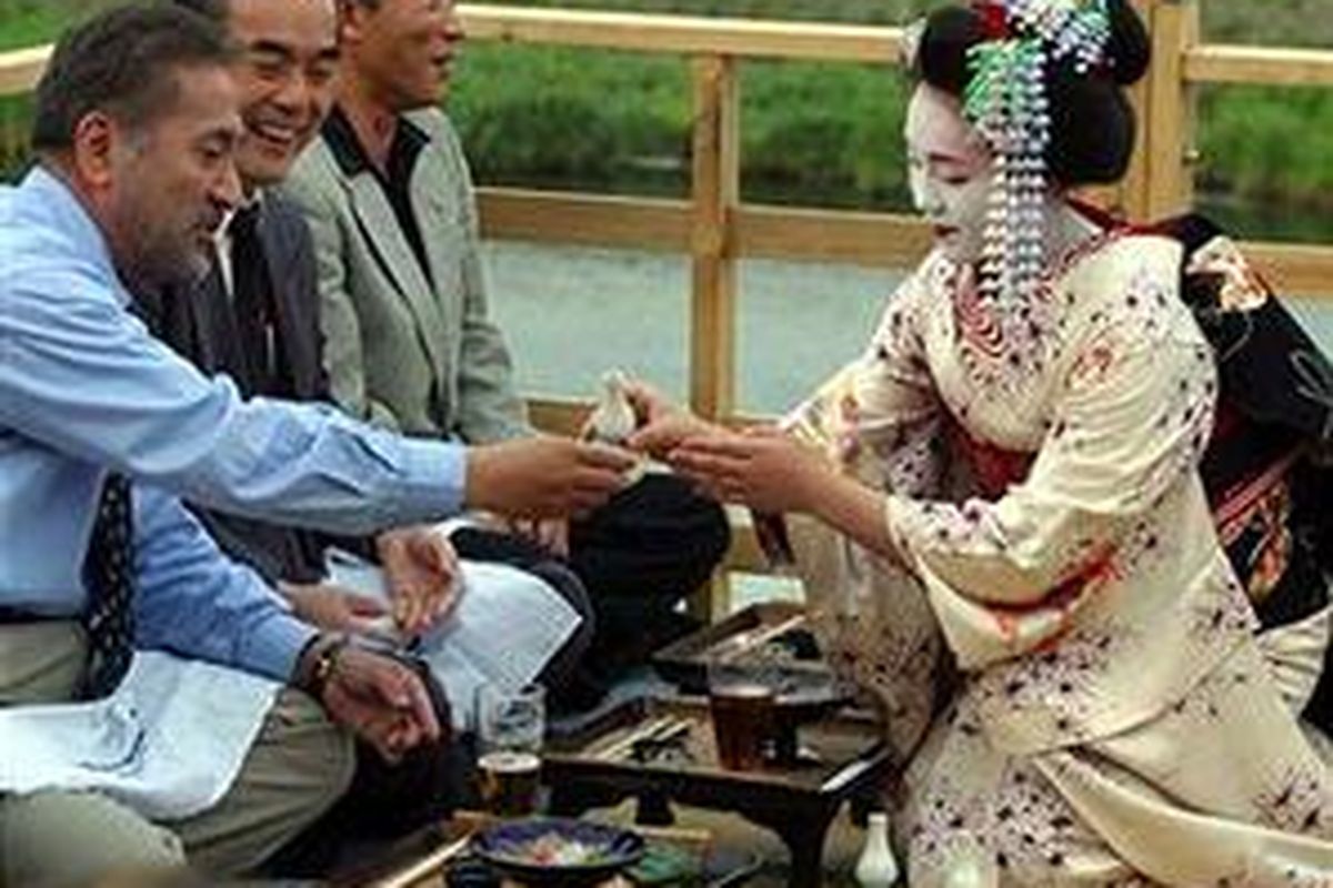 Seorang Maiko, penari jepang, dalam pakaian kimono tradisional, menuangkan sake untuk tamu-tamu di sebuah restoran di Sungai Kamogawa, Kyoto. Orang Jepang tidak biasa dengan budaya pemberian tip.