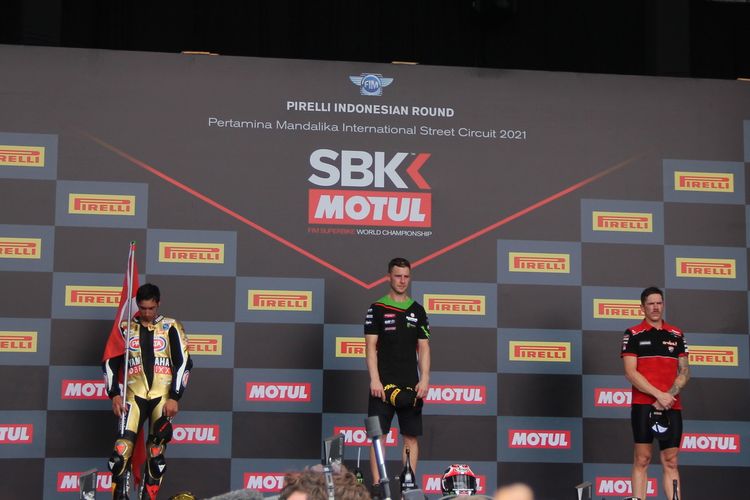 Pebalap Kawasaki Jonathan Rea (tengah) berdiri di podium Sirkuit Mandalika dengan diapit pebalap Yamaha Toprak Razgatlioglu (kiri) dan pebalap Ducati Scott Redding (kanan) usai Race 1 kelas World Superbike (WSBK) yang dihelat Minggu (21/11/2021). Meski memenangi balapan, Rea gagal mempertahankan gelar juara dunia yang sudah enam tahun beruntun ia raih.