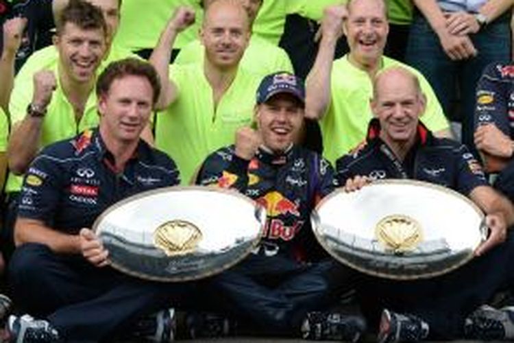 Pebalap Red Bull Racing asal Jerman, Sebastian Vettel (tengah) duduk di antara Christian Horner (kiri) dan Adrian Newey, berpose bersama seluruh tim, merayakan kemenangan mereka di Sirkuit Spa-Francorchamps, pada GP Berlgia, MInggu (25/8/2013),