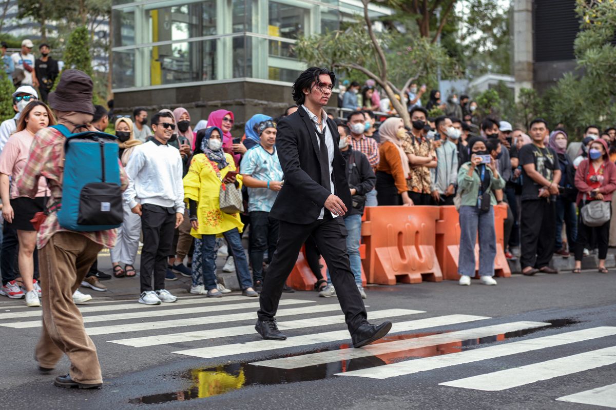 This picture taken on July 22, 2022 shows Indonesian youths presenting self-styled fashion creations at a pedestrian crossing turned catwalk, part of a gathering in recent weeks dubbed Citayam Fashion Week, in Jakarta. The crowd of fashionistas turning one of Jakarta's main commuter hubs into a makeshift catwalk have courted controversy in Indonesia's traffic-clogged capital, but their festival of style has become a site for free expression. (Photo by BAY ISMOYO / AFP) 