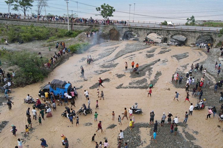 Foto udara pengendara melintasi sungai akibat jembatan amblas dan tidak dapat dilalui di Kelurahan Buluri di Palu, Sulawesi Tengah, Jumat (7/4/2023). Jembatan pada jalur penghubung Kota Palu dan Donggala hingga ke Sulawesi Barat dan Sulawesi Selatan serta menjadi salah satu jalur utama bagi pemudik tersebut terputus sehingga pengguna jalan terpaksa melintasi sungai.