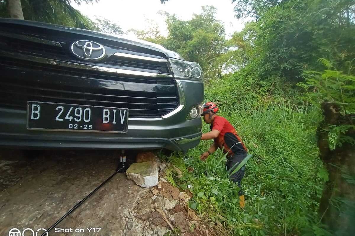 Petugas Damkar sedang mengevakuasi mobil Toyota Inova yang terperosok setelah mengikuti Google Maps di Tajurhalang, Kabupaten Bogor, Jawa Barat, Minggu (9/4/2023).