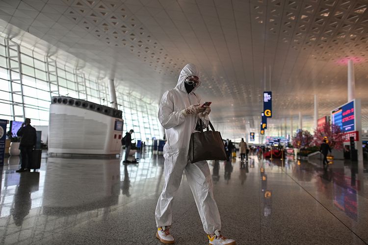 Seorang penumpang mengenakan pakaian pelindung diri melintas di Bandara Tianhe yang baru dibuka kembali di Wuhan, Hubei, China, Rabu (8/4/2020). Ribuan orang bergegas meninggalkan Wuhan setelah otoritas mencabut kebijakan lockdown selama lebih dari dua bulan di lokasi yang diketahui sebagai episenter awal virus corona tersebut.