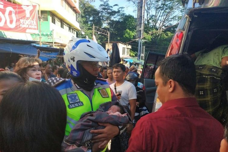 Seorang anggota lalu lintas Polresta Bogor Kota menggendong bayi yang baru dilahirkan di Pasar Bogor, Rabu (3/4/2019).