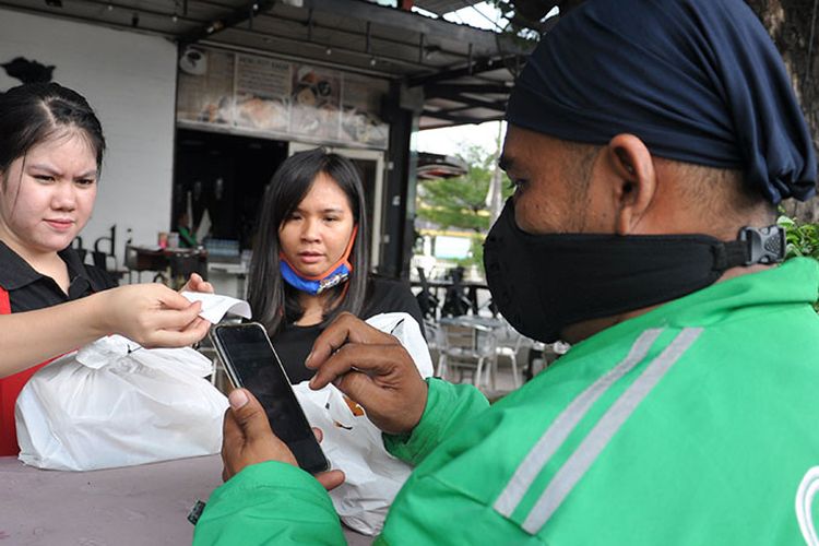 Karyawan restoran melayani pengemudi ojek online yang menerima pesanan milik pelanggannya melalui aplikasi di salah satu tempat pusat kuliner di kawasan Merdeka Walk Medan, Sumatera Utara, Selasa (24/3/2020). Pengelola menghentikan melayani pembeli yang makan dan minum di tempat dan menggantinya dengan menerima pesanan take-away atau dibungkus untuk dibawa pulang guna mengantisipasi wabah COVID-19.