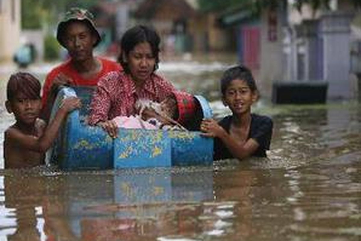 Seorang ibu dan anak yang terjebak banjir di Kampung Mekarsari Cieuntung, Kelurahan Baleendah, Kecamatan Baleendah, Kabupaten Bandung menggunakan bekas boks telepon umum. 