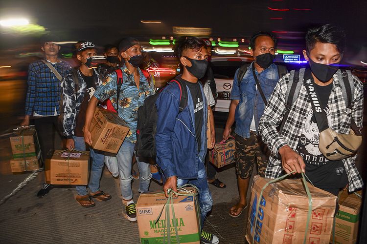 Calon pemudik yang terjaring razia penyekatan berjalan menaiki bus yang akan membawa mereka ke Terminal Pulogebang, Jakarta, di Pintu Tol Cikarang Barat, Bekasi, Jawa Barat, Kamis (21/5/2020). Calon pemudik yang terjaring razia penyekatan oleh Polda Metro Jaya tersebut dibawa ke Terminal Pulo Gebang untuk kemudian diarahkan kembali menuju Jakarta.