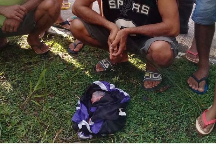 Warga sebuah desa di provinsi Negros Oriental, Filipina membungkus bayi yang dibuang di jalanan dengan menggunakan kain.