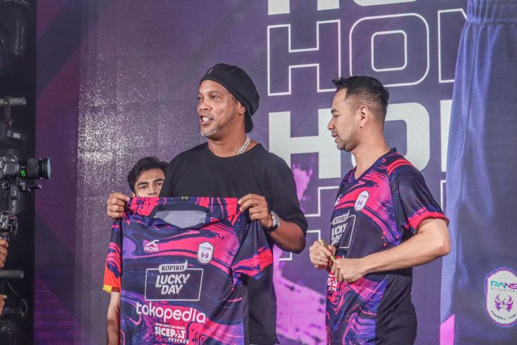 Mantan pesepak bola dunia asal Brasil Ronaldinho (tengah) memegang jersey baru RANS Nusantara FC di Jakarta, Jumat (24/6/2022). RANS Nusantara FC meluncurkan seragam anyar untuk menghadapi musim Liga 1 Indonesia 2022-2023.