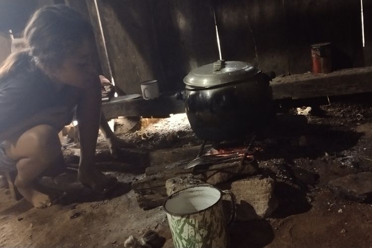 Karolina Verawati (11), seorang anak yatim piatu di kampung Racang, Desa Colol, Kecamatan Lambaleda Timur, Kab. Manggarai Timur, NTT sedang masak nasi di dapurnya, Kamis, (27/1/2022). (KOMPAS.com/MARKUS MAKUR)
