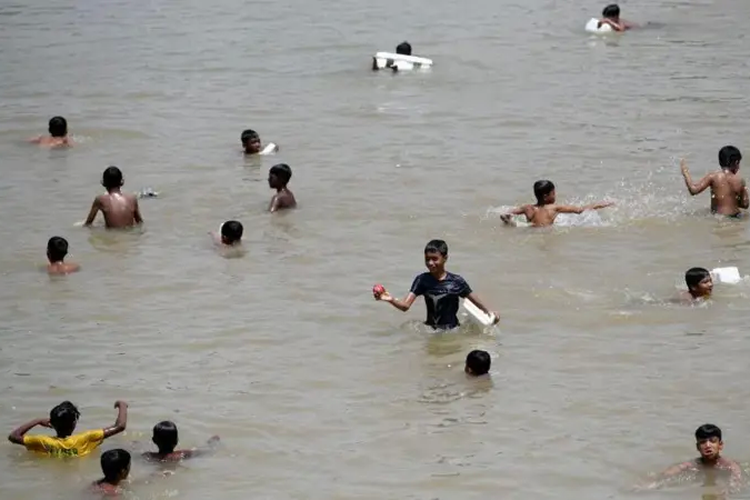 Anak-anak mendinginkan diri di sebuah danau pada hari yang panas di Dhaka.