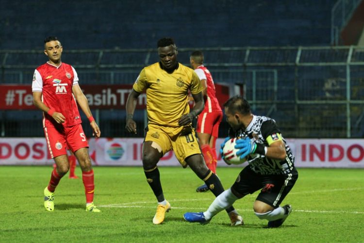 Penyerang Bhayangkara FC, Ezechiel Ndouassel, berduel dengan kiper Persija, Andritany Ardhiyasa, pada laga Persija Jakarta vs Bhayangkara Solo FC di Grup B Piala Menpora 2021 di Stadion Kanjuruhan, Malang, Jawa Timur pada Rabu (31/3/2021) sore hari WIB.