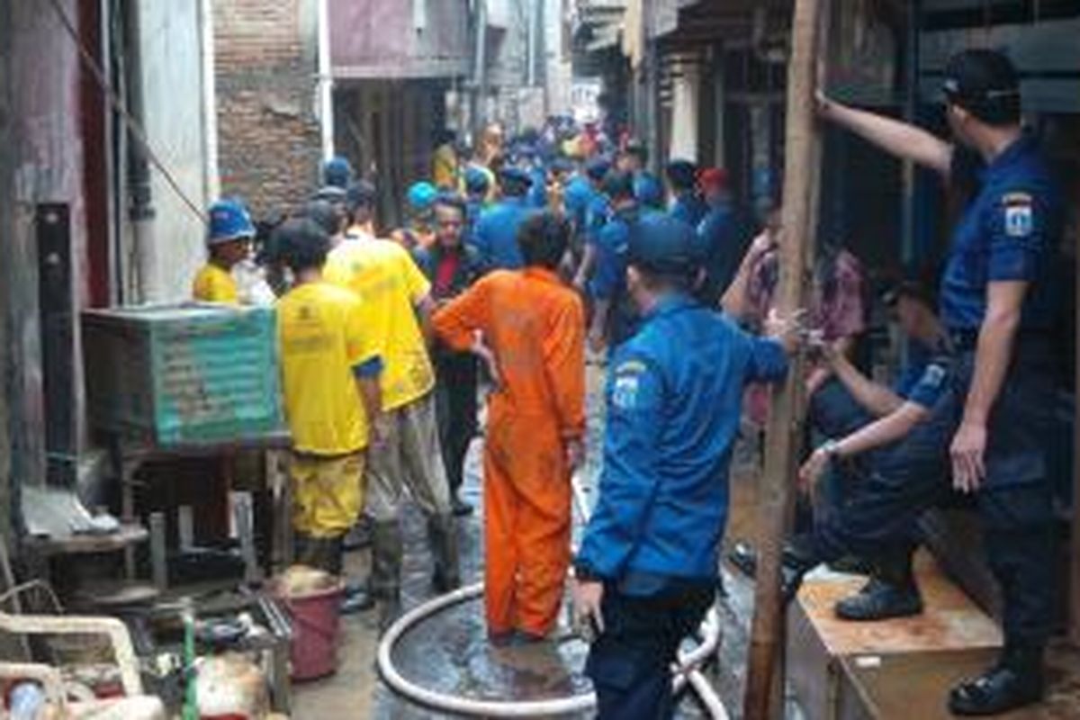 Petugas melakukan pembersihan lumpur di Kampung Pulo, Jatinegara, Jakarta Timur. Kamis (13/2/2014).