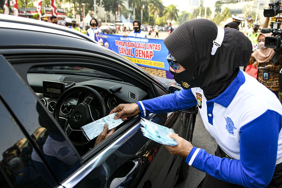 Anggota Polisi wanita (Polwan) membagikan masker pada pengendara mobil saat sosialisasi pemberlakuan kembali ganjil genap di Bundaran Hotel Indonesia, Jakarta, Minggu (2/8/2020). Pemprov DKI Jakarta menerapkan kembali aturan ganjil genap bagi kendaraan roda empat saat masa Pembatasan Sosial Berskala Besar (PSBB) transisi mulai Senin (3/8/2020) di 25 ruas jalan Ibu Kota.