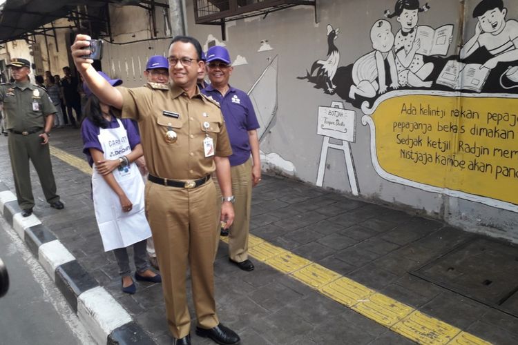 Gubernur DKI Jakarta Anies Baswedan berswafoto di depan sebuah mural di kawasan Penjaringan, Selasa (31/7/2018). 