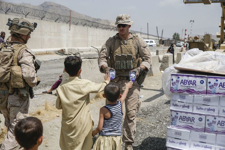 Foto dari Marinir Amerika Serikat menunjukkan seorang tentara Korps Angkatan Laut AS bersama anggota Gugus Tugas Marinir Udara-Darat Tujuan Khusus di Pusat Komando, memberikan air minum kepada anak-anak saat evakuasi penduduk di bandara internasional Hamid Karzai, Kabul, Afghanistan, Jumat (20/8/2021).