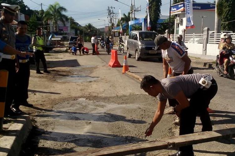 Foto Suasana Belasan Anggota Lantas Polres Poso Dan Warga Perbaiki Jalan Rusak Pada Selasa (21/2/2017)