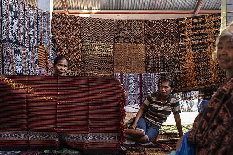 Pengrajin menunjukkan motif kain tenun ikat kepada calon pembeli di Pasar Alok, Maumere, Sikka, Nusa Tenggara Timur (NTT), Selasa (31/7/2018). Di Pasar Alok, setiap Selasa mulai pukul 06.0013.00 Wita merupakan hari khusus bagi perajin seantero Kabupaten Sikka dan daerah lainnya untuk menjual kain tenun ikat hasil kerajinan tangan yang dibuat dengan mesin tenun tradisonal.