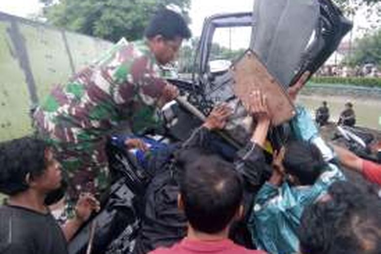 Seorang anggota TNI bersama warga brrjibaku mengeluarkan sopir mobil yang terjepit akibat terlibat kecelakaan dengan truk bok yang terjadi di Jalur Pantura Demak, Kamis (24/11/2016) pagi. 