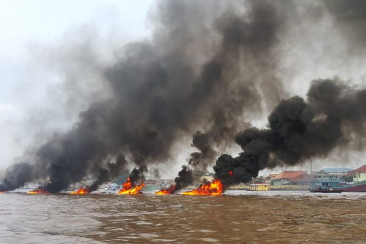 Serpihan perahu jukung yang meledak di perairan sungai Musi Palembang, Sumatera Selatan menyebabkan kepulan asap yang menutup badan jembatan Ampera, Kamis (20/12/2018).
