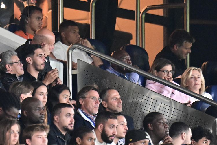 Penyerang Paris Saint-Germain (PSG) Kylian Mbappe (atas, kaus putih) berada di tibune pertandingan saat laga Ligue 1 antara PSG vs Lorient di Stadion Parc des Princes di Paris pada Minggu 13 Agustus 2023 dini hari WIB.