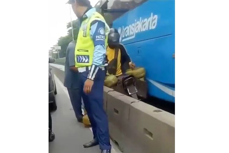 Tangkapan layar dari sebuah video viral tentang pengendara sepeda motor yang bermuatan tabung gas LPG 3 Kg tengah berhimpitan dengan bus Transjakarta.