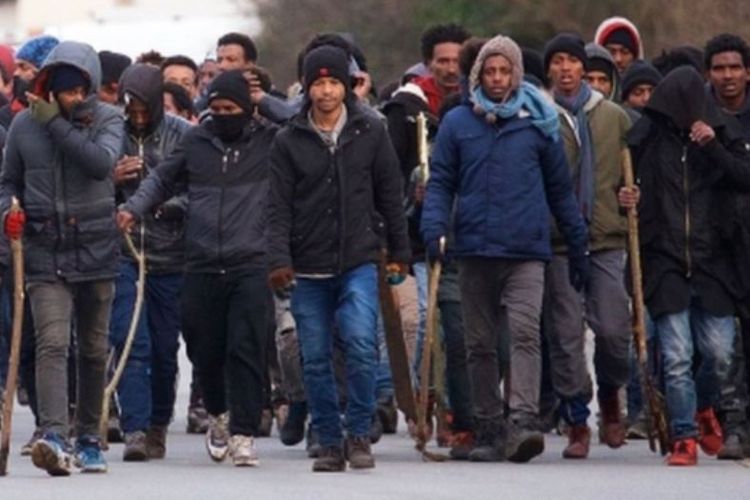 Sekelompok migran menggunakan tongkat selama bentrokan terjadi. (EPA via BBC)