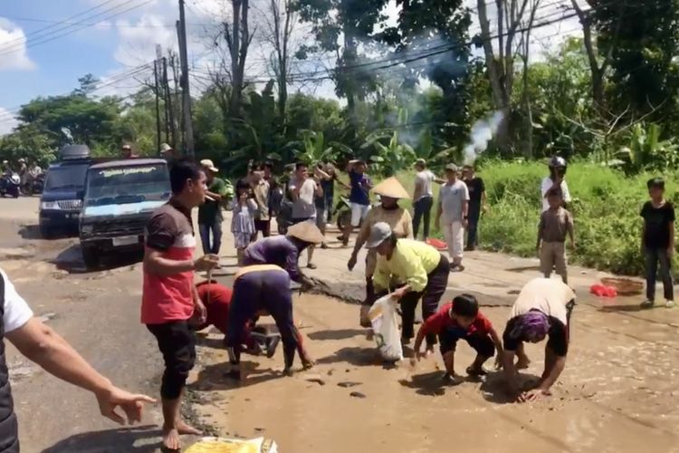 Para warga menabur dan menangkapi ikan di lubang jalan di jalan kecamatan Sukadana, Lampung Timur, Senin (22/4/2024). Aksi ini dilakukan untuk menyindir Pemkab Lampung Timur yang tidak juga memperbaiki jalan.