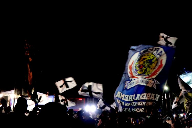Sejumlah orang mengibarkan bendera Arema saat doa bersama dengan tema Tabligh Akbar dan Doa bersama Mengenang 100 hari Tragadi Kanjuruhan yang digelar halaman Stadion Kanjuruhan Kepanjen, Kabupaten Malang, Minggu (8/1/2023) malam.