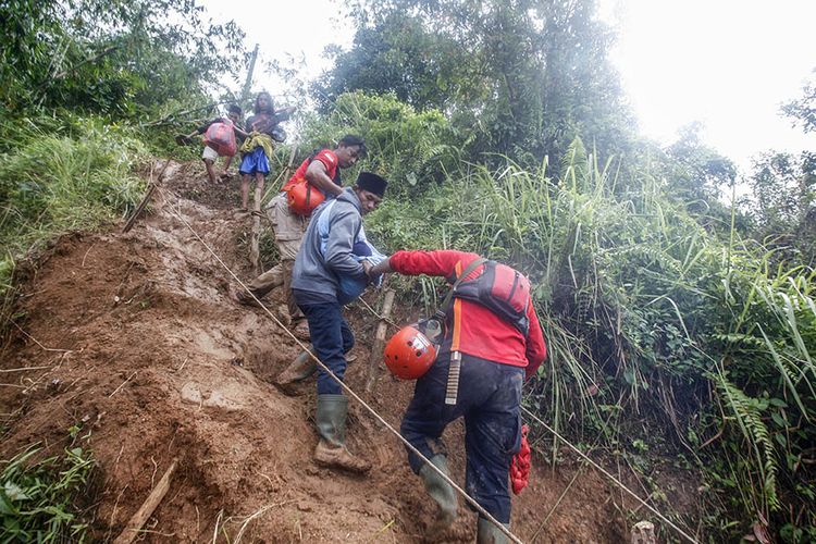 Polmas (Perpolisian Masyarakat) membantu evakuasi warga melewati jalur darurat bencana dan longsor di Desa Harkat Jaya, Kecamatan Sukajaya, Kabupaten Bogor, Jawa Barat, Sabtu (4/1/2020). Untuk mencapai dua dusun terisolasi yaitu desa Kiarapandak dan Desa Urug relawan maupun warga harus berjalan sejauh 8 kilometer melalui jalur darurat.