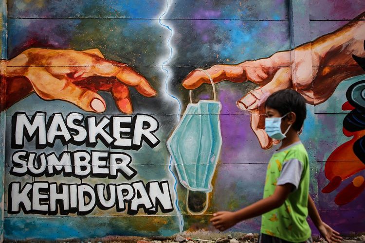 Seorang bocah melintas di depan mural tentang penggunaan masker di Kota Tangerang, Banten, Minggu (21/12/2020). Mural tersebut dibuat sebagai edukasi kepada masyarakat untuk selalu menggunakan masker guna mencegah penyebaran COVID-19. ANTARA FOTO/Fauzan/aww.