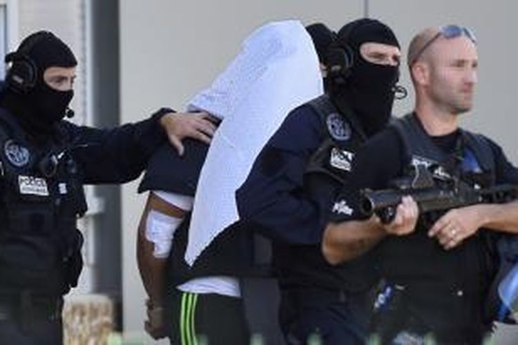 Sejumlah petugas kepolisian Perancis menggiring Yassin Salhi (kepala tertutup), tersangka pemenggalan dan percobaan peledakan sebuah perusahaan gas di dekat kota Lyon pada Jumat (26/6/2015).