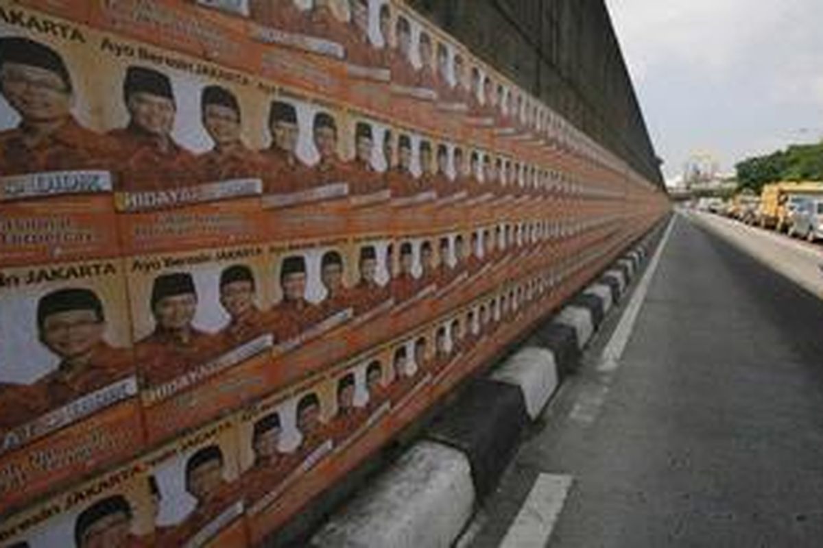Poster kampanye salah satu pasangan calon gubernur dan wakil gubernur terpasang hampir 20 meter lebih panjangnya di dinding fly over sisi jalur bus TransJakarta di kawasan Pancoran, jakarta, Rabu (13/6/2012). Poster dan selebaran serupa banyak dipasang di fasilitas umum menjelang Pilkada DKI. 