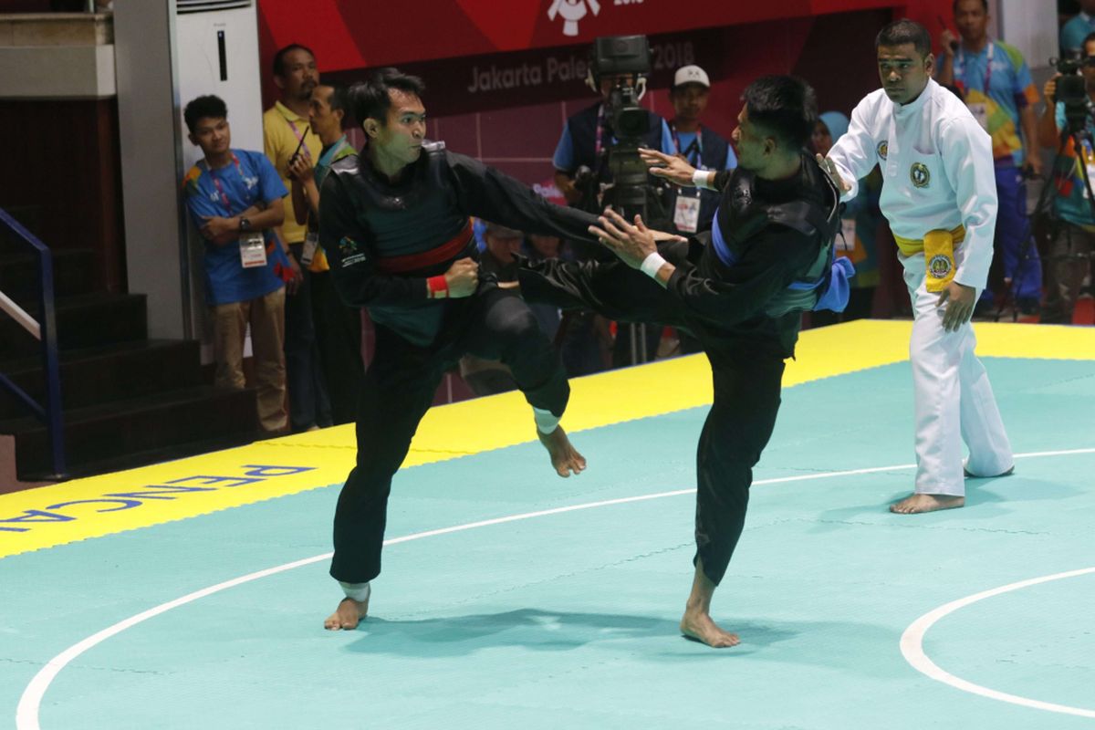 Pesilat Indonesia Komang Harik Adi Putra (sabuk merah) melakukan serangan  kepada pesilat Malaysia Mohd Al Jufferi Jamari dalam babak final Kelas E Putra Asian Games 2018 di Padepokan Pencak Silat Taman Mini Indonesia Indah (TMII), Jakarta, Senin (27/8/2018). Komang berhasil meraih medali emas cabang olahraga pencak silat kelas 65-70 kilogram.