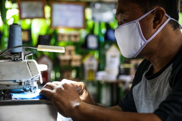 Warga menjait masker berbahan kain di Kampung Anggur, Kota Tangerang, Banten, Kamis (9/4/2020). Untuk menanggulangi penyebaran virus Covid-19, warga kampung anggrek secara swadaya memproduksi masker dan dibagikan kepada masyarakat sekitar.
