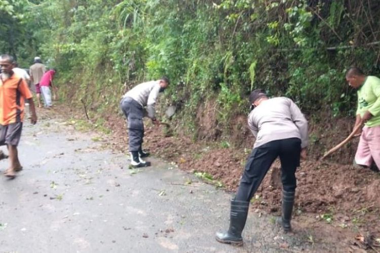 Sejumlah petugas Polsek Gemarang membantu warga membersihkan material tanah longsor yang terjadi di Desa Durenan, Kecamatan Gemarang, Kabupaten Madiun, Jatim, Kamis (10/3/2022). Bencana tersebut sempat memutuskan jalan Desa Durenan menuju Desa Batok akibat tertutup material tanah longsor. 