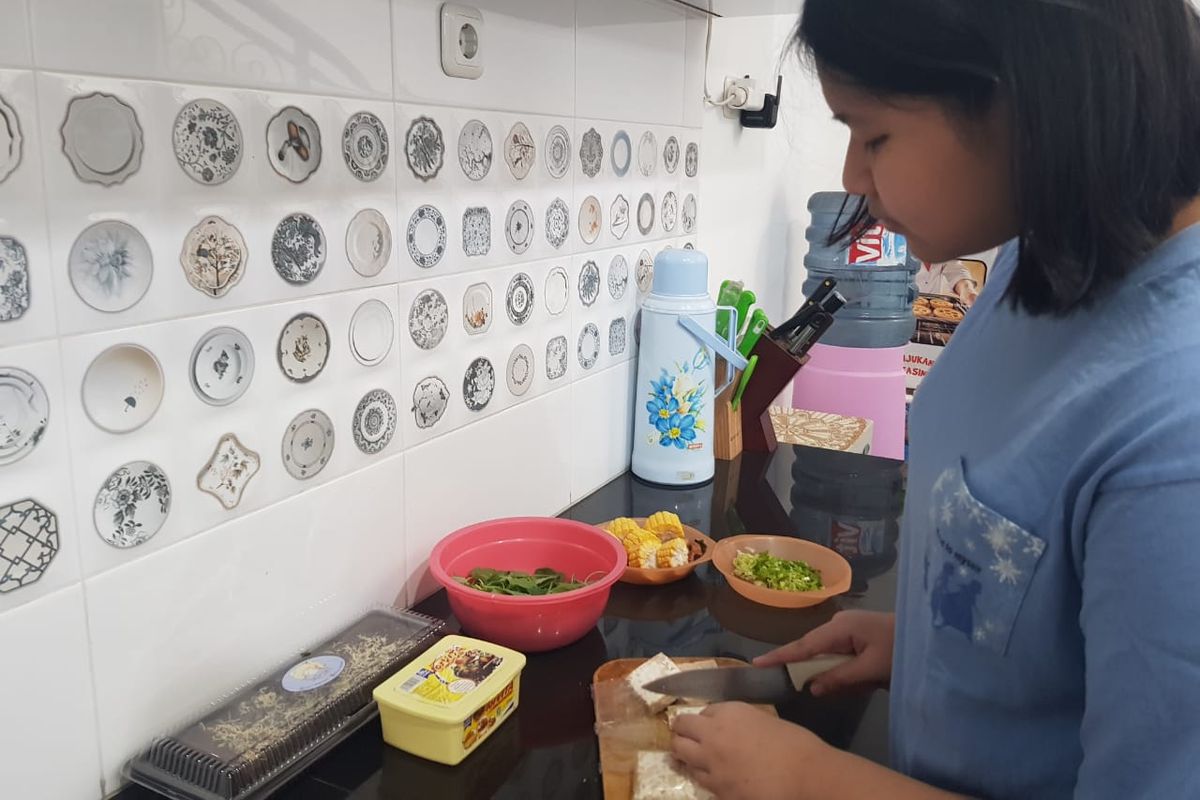 Naira Callista Maheswari (15) sedang memasak di dapur rumahnya. Naira Butuh waktu untuk melepaskan stress akibat tak diterima di SMA negeri pilihannya lewat Penerimaan Peserta Didik Baru (PPDB) DKI Jakarta 2020 jalur zonasi. Hobi memasak ia jalankan untuk melepas stres. Video-video memasak di Youtube ia tonton dan lalu dipraktekkan. Hobinya pun membawa untung.