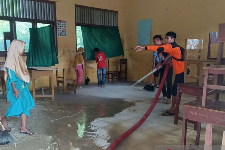 Petugas BPBD Aceh Tenggara dan siswa membersihkan ruang kelas yang berlumpur akibat banjir di Aceh Tenggara. 
