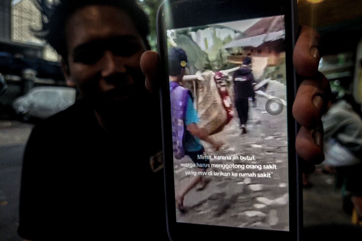 Sebuah rekaman video menunjukkan seorang pasien yang ditandu menggunakan kain sarung dan bilah bambu melintas di sebuah jalan viral di media sosial, Senin (21/4/2025).