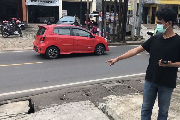 Seoramg warga menunjukkan tutup besi gorong-gorong di pinggir Jalan Sawangan Raya, Pancoran Mas, Kota Depok, Jawa Barat yang digasak maling pada Senin (15/11/2021) sore.