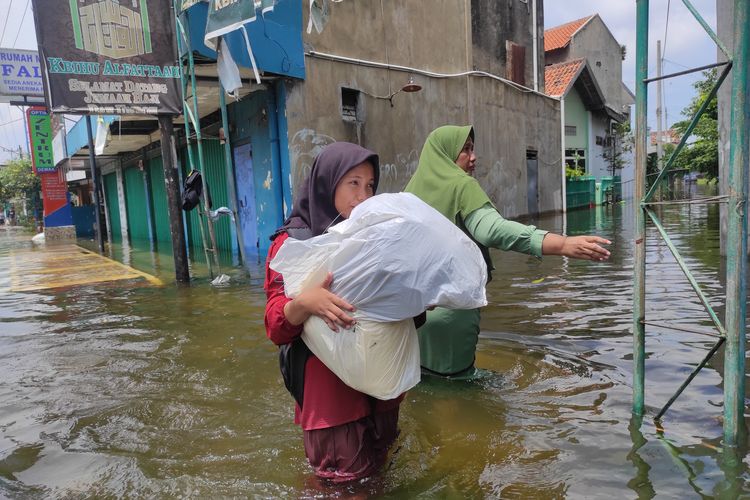 Pelajar menerjang banjir di Kelurahan Bintoro, Kecamatan Demak, Kabupaten Demak, Selasa (19/3/2024). (KOMPAS.COM/NUR ZAIDI)
