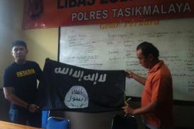 Petugas Satreskrim Polres Tasikmalaya menunjukkan barang bukti bendera ISIS di Mako Polres Tasikmalaya, Senin (11/8/2014).