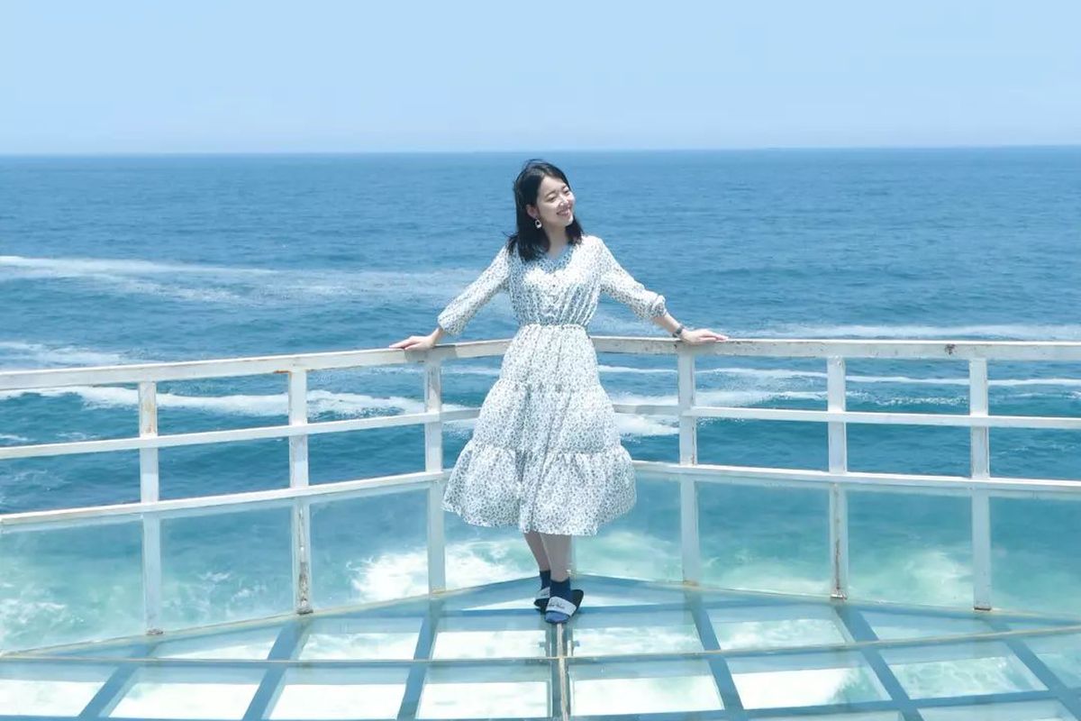 Pengunjung berfoto di balkon dari kaca yang menjadi ikon dari Teras Kaca Pantai Nguluran.
