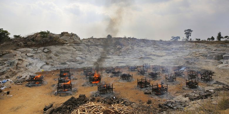 Tumpukan kayu pemakaman dua puluh lima korban COVID-19 dibakar di krematorium terbuka yang didirikan di tambang granit di pinggiran Bengaluru, India, Rabu (5/5/2021).