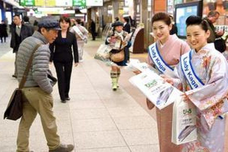 Dua Lady Kaga sedang membagikan brosur pariwisata untuk Perfektur Kaga di Jepang. 