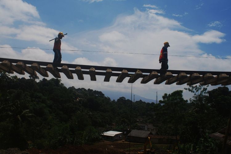 Dua orang pekerja sedang melintas di atas rel kereta api jurusan Bogor-Sukabumi yang terdampak longsor di Kampung Maseng, Desa Warung Menteng, Kecamatan Cijeruk, Kabupaten Bogor, Kamis (8/2/2018).